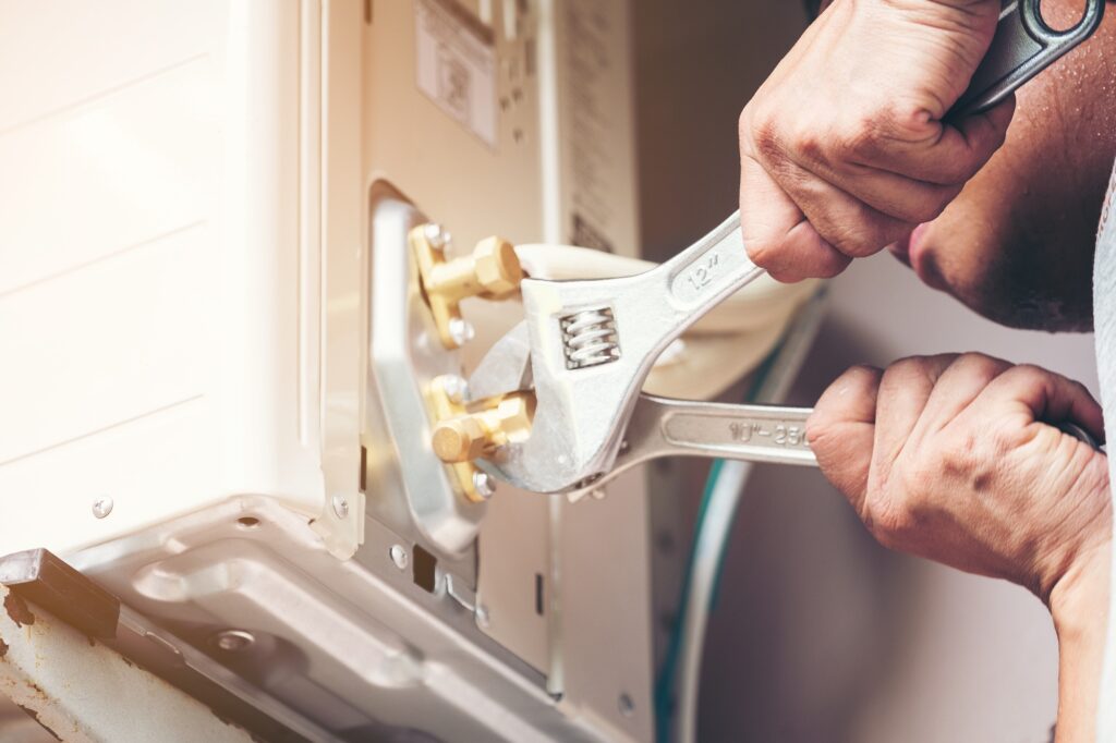 Technician hand using fix wrench to tighten outdoor unit of air condition
